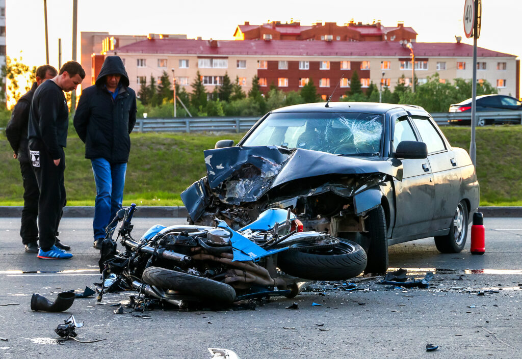 motorcycle laying on the road after being hit by a car