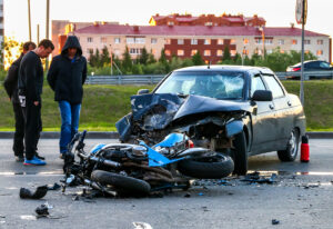 motorcycle laying on the road after being hit by a car